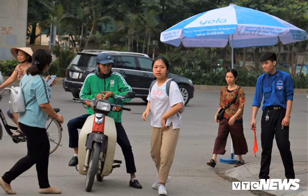 Một học sinh đi xe ôm đến trường được tình nguyện viên hướng dẫn khi gần đến giờ thi.