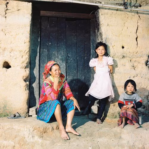 Một gia đình người Mông trước cửa nhà. Ngôi nhà đơn sơ với tường được đắp bằng đất vẫn là kiểu nhà phổ biến cửa người Mông tại các tỉnh vùng núi phía Bắc (Nhà trình tường). Bức ảnh được chụp tại một bản nhỏ gần thị trấn Vinh Quang - Hoàng Su Phì.