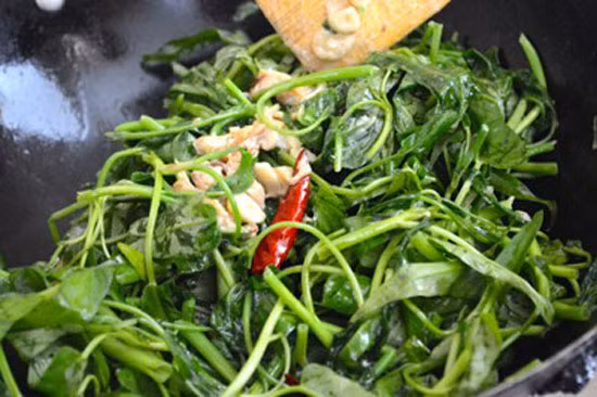 Phi thơm tỏi, cho rau muống, xì dầu, bột ngọt vào, đảo đều.