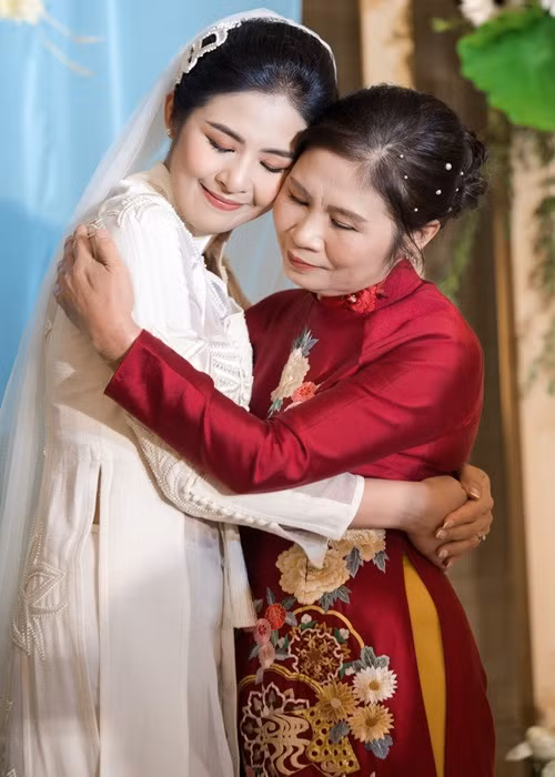 Mẹ đẻ của Ngọc Hân diện áo dài đỏ do con gái thiết kế. Ảnh: Zing