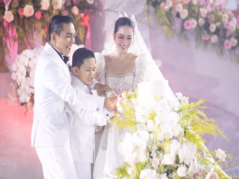 Cặp đôi cùng con trai thực hiện nghi lễ cắt bánh cưới.
