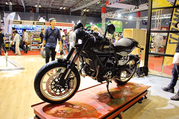 Dựa trên phiên bản Scrambler Full Throttle trước đây, Scrambler Cafe Racer vẫn sử dụng chung nhiều chi tiết quan trọng như khung chính, phuộc, đèn pha... Ở phía trước, khác biệt đầu tiên của chiếc xe đó là một tấm nhựa bao kín viền đèn pha và phần nối với bảng đồng hồ, khiến chiếc xe trông gọn gàng hơn. Cặp xi-nhan của phiên bản này cũng được rút gọn.