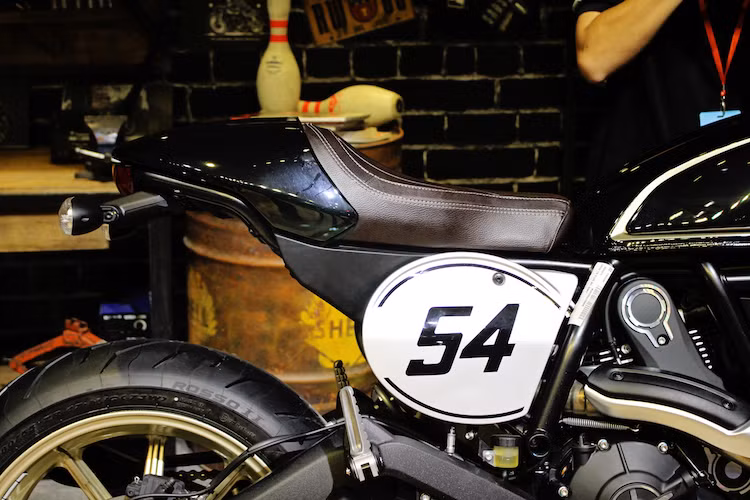 Ở hai bên thân xe, Scrambler Cafe Racer có 2 miếng nhôm in số 54 theo đúng phong cách những chiếc xe đua cổ điển. Số 54 mang ý nghĩa gợi nhớ về con số gắn liền với tay đua huyền thoại từng "đầu quân" cho Ducati là Bruno Spaggiari. Ở phía sau, chiếc xe có phần đuôi khác biệt so với các phiên bản khác, với "gò" nhựa theo đúng phong cách cafe racer và yên solo bọc da, chần chỉ múi dọc đậm chất cổ điển.