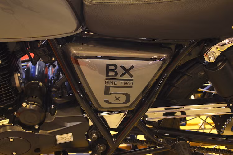 Nằm hai bên thân xe, những tấm ốp được dán decal chữ BX125 được cách điệu khá độc đáo. Chiếc BX125 Classic tại triển lãm được sơn màu xám nòng súng kết hợp với xám, giữa 2 màu này được ngăn cách với nhau bởi các đường viền chỉ màu đen. Logo nổi Brixton trên bình xăng khiến chiếc xe trông cao cấp hơn.