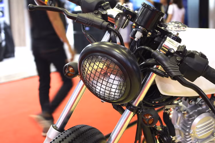 Với gói độ cafe racer, ngoại hình của GD110 đã thay đổi gần như hoàn toàn, chỉ còn giữ lại một số chi tiết nguyên bản quan trọng. Ở phía trước, chiếc xe đã được thay bộ đèn pha chóa tròn với lưới chắn theo phong cách xe quân sự, kèm theo 2 xi-nhan nhỏ nhắn hơn gắn hai bên phuộc.