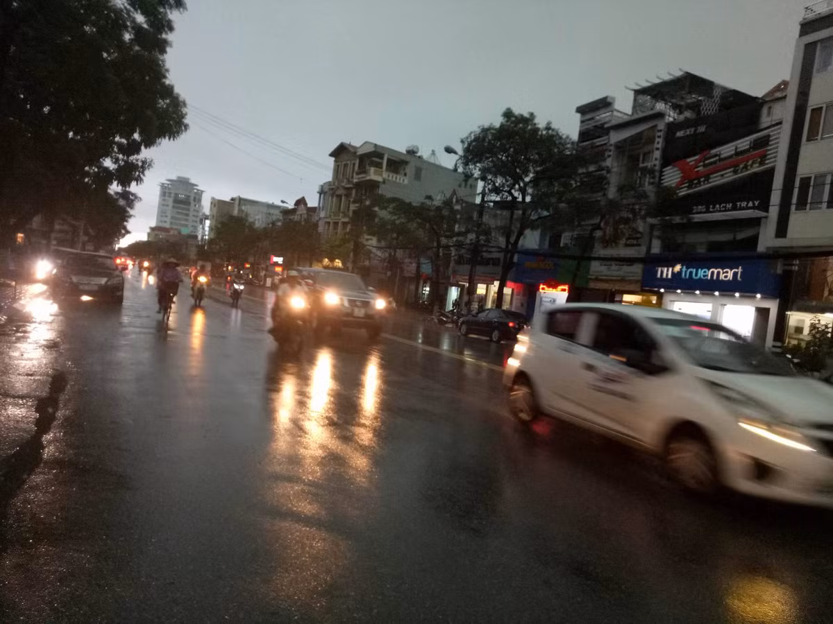 Trước khi mưa nặng hạt đổ xuống, đường phố Hải Phòng tối om do mây mù bao phủ, nhiều phương tiện lưu thông phải bật đèn.