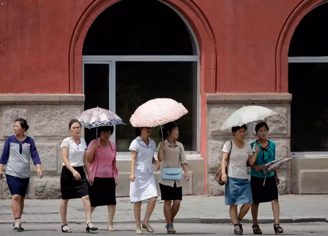 Những người phụ nữ che ô khi đi trên đường phố trung tâm Bình Nhưỡng ngày 26/7/2017.