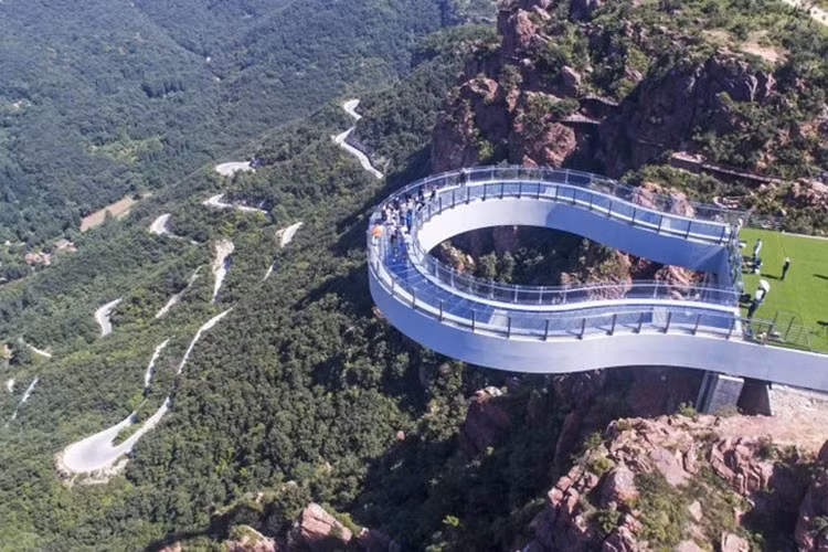 Fuxi Mountain Skywalk: Nằm ở núi Phục Hy (Hà Nam), "lối đi trên không" hình móng ngựa bằng thép và kính này nặng đến 3.000 tấn, vừa mở cửa cách đây không lâu. Từ vách núi nhô ra đến 30 m, Fuxi Mountain Skywalk đã phá vỡ kỷ lục của công trình tương tự là Arizona's Grand Canyon Skywalk (Mỹ). Chỉ những du khách đủ dũng cảm mới dám nhìn vực sâu 360 m bên dưới qua lớp kính trong suốt. Ảnh: Ecns.cn.