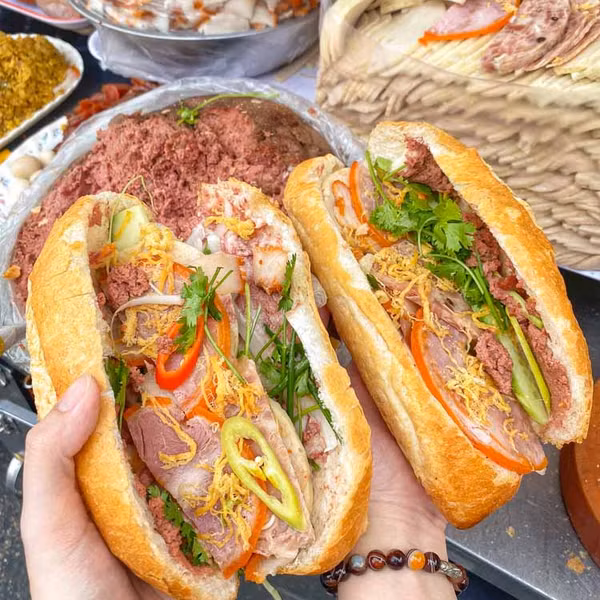 Điểm khởi đầu lý tưởng cho hành trình khám phá ẩm thực chính là bánh mì – món ăn đã trở thành biểu tượng không thể thiếu của Việt Nam trên bản đồ ẩm thực thế giới. Bánh mì Sài Gòn có thể đơn giản chỉ là pate, chả, hoặc phong phú hơn với thịt nướng, xíu mại, trứng muối… Nhưng điều làm nên sự khác biệt là nước sốt béo ngậy, đậm đà, cùng lớp vỏ bánh giòn rụm bên ngoài, mềm mại bên trong. Ảnh amthucviet