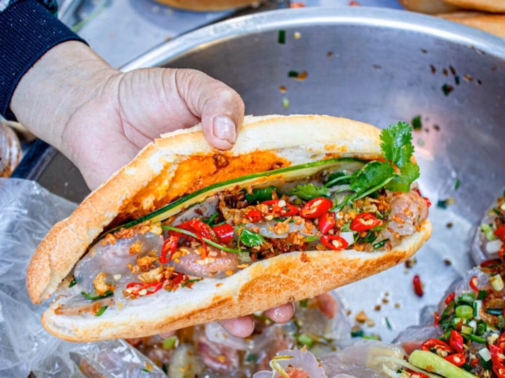 Bánh bột lọc không còn xa lạ gì với du khách đến miền Trung, nhưng ở Quảng Bình có món ăn khá độc đáo là bánh mì kẹp bột lọc. Những viên bột lọc nhân tôm và nhân đậu xanh được chủ quán nhanh tay bỏ vào trong bánh mì còn nóng, chan thêm nước sốt cay. Ảnh Internet
