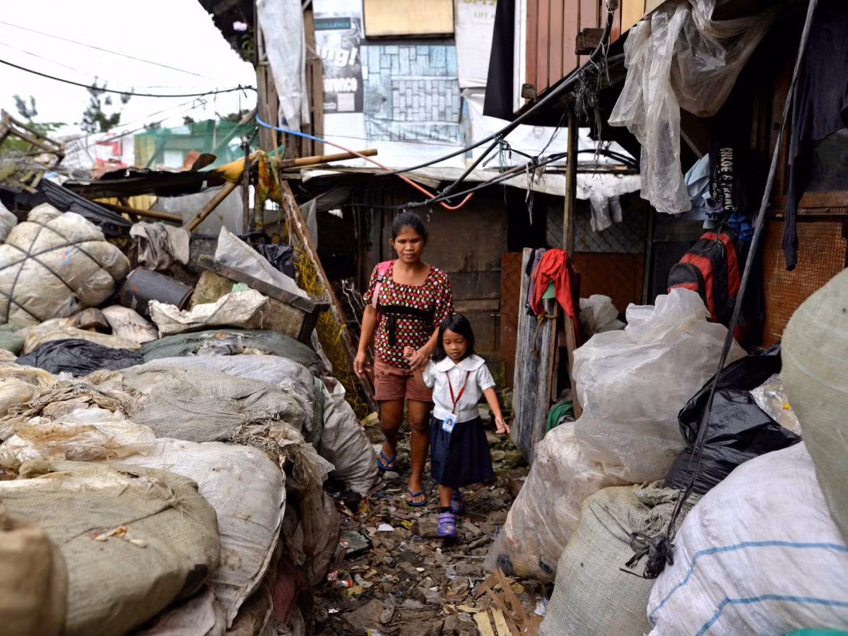  Manila nằm trên bờ biển phía tây bắc Philippines. Thành phố này chứa một khu kinh doanh bùng nổ, khu dân cư, khu ổ chuột và các khu ổ chuột ở rìa. Ở những khu vực nghèo nhất, nhiều gia đình phải sống trong các ngôi nhà tạm dọc theo các con sông. Ảnh: Cô Weng Ruda, 36 tuổi, đưa con gái đi học ở khu ổ chuột tại Manila. (Nguồn: BI)