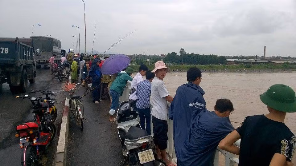 Hàng chục người dân đứng trên thành cầu Bình thả cần câu cá xổng lồng.