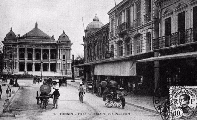 Khu vực Nhà hát lớn và phố Paul Bert (Tràng Tiền). Ngoài hình ảnh người kéo xe tay, xích lô cùng viên cảnh sát đi xe đạp, thấy rõ xe bò chở nước.