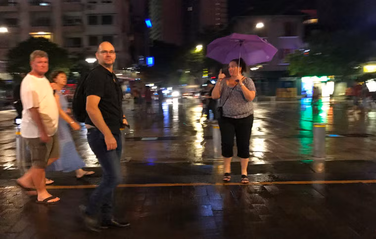 Du khách nước ngoài sử dụng ô (dù) che mưa để đi dạo trên phố đi bộ Nguyễn Huệ.
