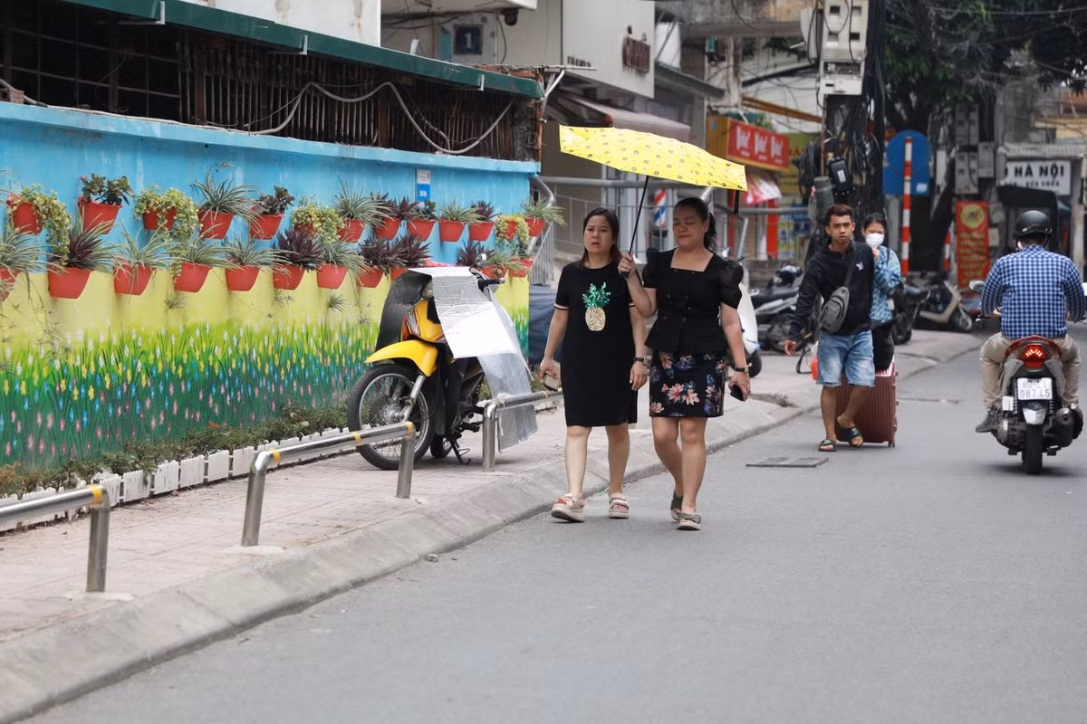 Một xe máy ngang nhiên đỗ trên vỉa hè, đẩy người đi bộ xuống lòng đường.