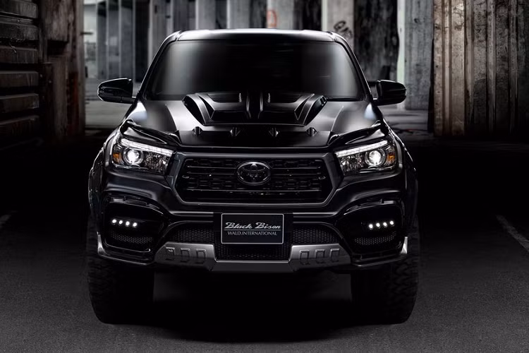 Về tổng quan, chiếc Toyota Hilux Black Bison 2020 mới của Wald toát lên một vẻ hung dữ nhờ nước sơn đen tối màu, cùng nhiều chi tiết độ như các vòm bánh cỡ lớn, bộ lốp địa hình chuyên dụng, tấm nắp gân guốc trên mui xe, và nhiều chi tiết khác.