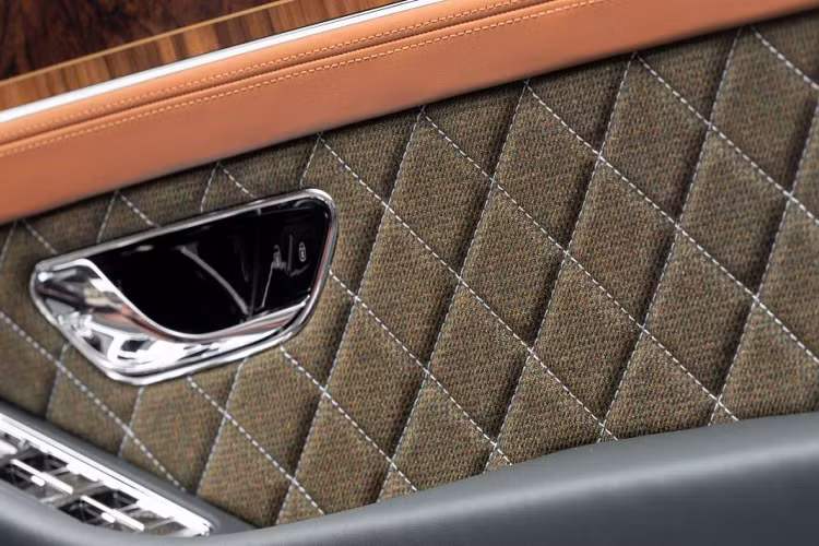 Ngoài ra, các tấm cửa được bọc vải tweed với họa tiết kim cương, gỗ veneer Burr Walnut trên mặt bảng điều khiển, ngăn xếp trung tâm và bảng điều khiển. 