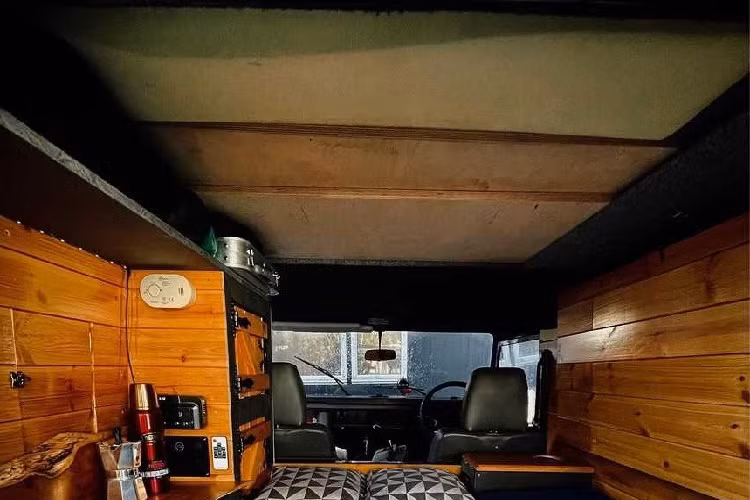 Nhìn bên ngoài, chiếc Land Rover Defender cổ điển này có thân màu xanh đậm với các sọc trắng chạy dọc hai bên. Giá đỡ trên nóc có thể trượt để nhường chỗ cho phần nóc mở lên.