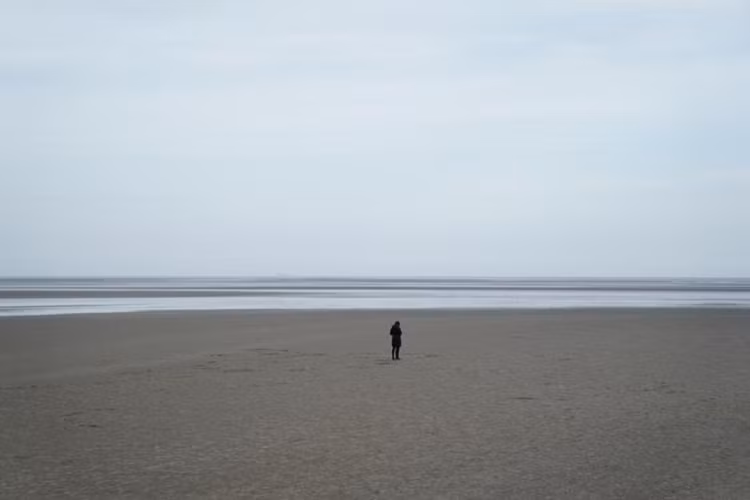Một người phụ nữ đứng trên bờ biển Sandymount vắng người ở Dublin, Ireland, ngày 23/3.