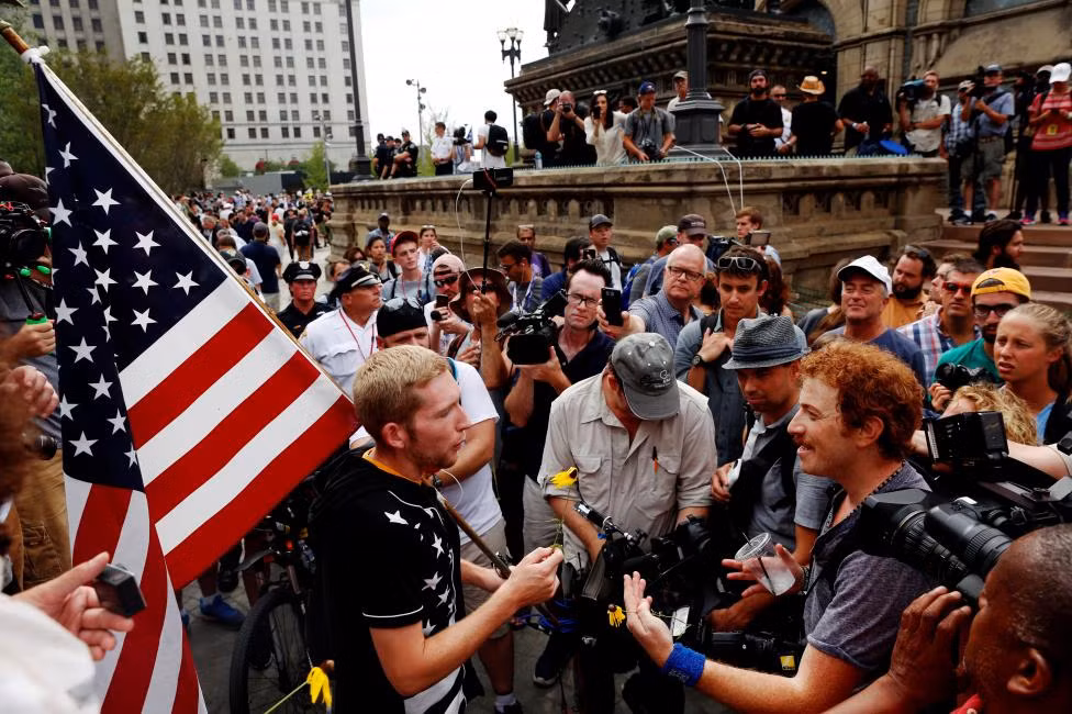 Người đàn ông tranh luận với một người ủng hộ tỷ phú Donald Trump đang cầm lá cờ Mỹ gần nơi diễn ra Đại hội toàn quốc Đảng Cộng hòa (RNC) ở Cleveland, bang Ohio, hôm 21/7/2016. Được biết, tỷ phú Donald Trump đã chính thức được đề cử đại diện của Đảng Cộng hòa ra tranh cử Tổng thống Mỹ năm 2016.