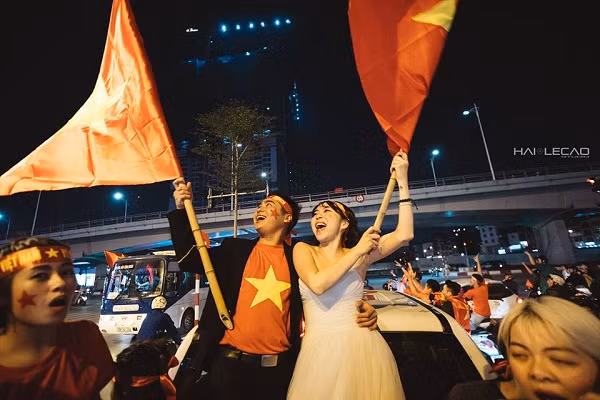 Hòa vào dòng người đổ ra đường với nồi niêu, xoong chảo, kèn, trống, cờ hoa... để cổ vũ cho chiến tích lịch sử của đội tuyển U23 Việt Nam, là một cặp đôi cô dâu - chú rể Hà thành gây sốt với bộ ảnh cưới "không thể độc hơn".