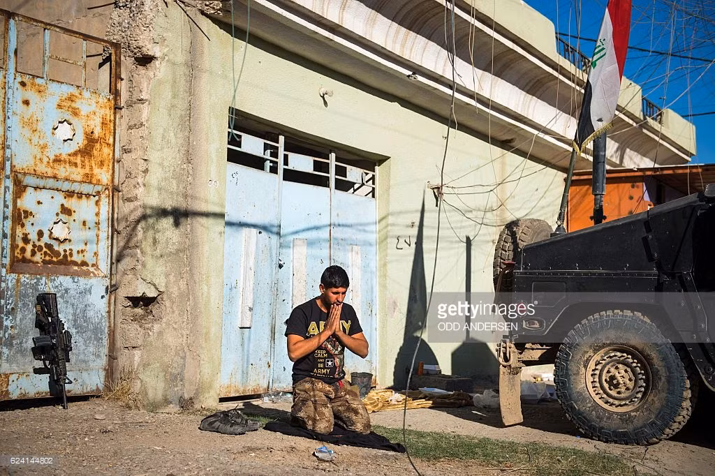 Một người lính Iraq cầu nguyện gần xe bọc thép Humvee ở Karkukli cùng ngày. Ảnh GT
