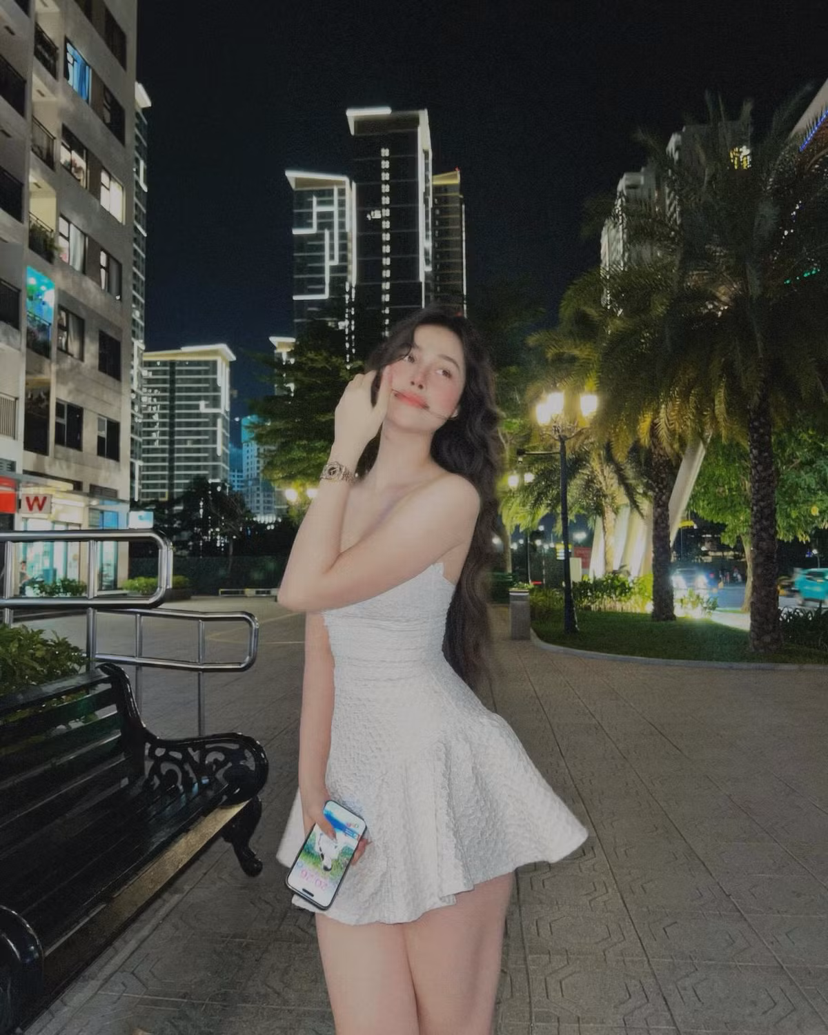 Diện bộ váy trắng ôm sát dáng, Hồng Vy không chỉ tôn lên đường cong quyến rũ mà còn toát lên thần thái rạng rỡ đầy sức sống, khiến khung cảnh thành phố về đêm như trở nên thơ mộng hơn hẳn.