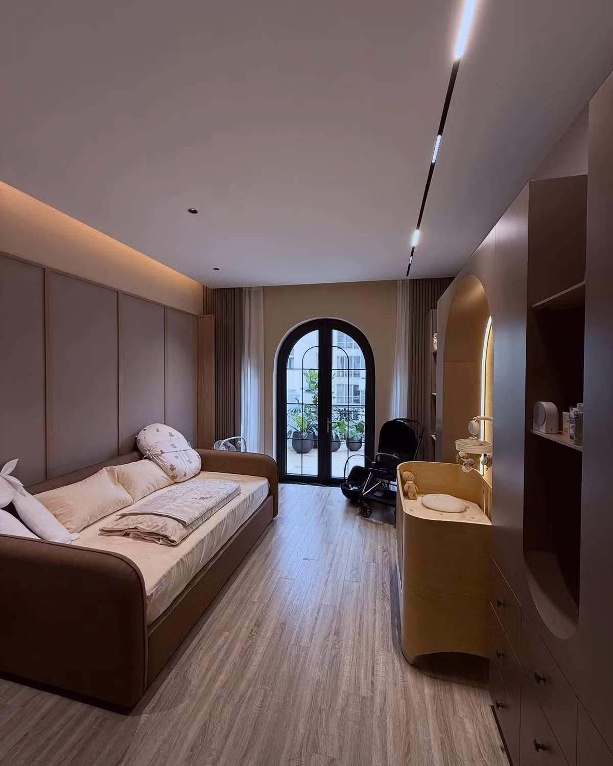 Phòng chính dành để chăm sóc em bé được thiết kế tối giản nhưng không kém phần sang trọng, với giường ngủ bọc da và cửa sổ lớn hướng ra ban công, mang lại không gian thoáng đãng và tràn ngập ánh sáng tự nhiên.