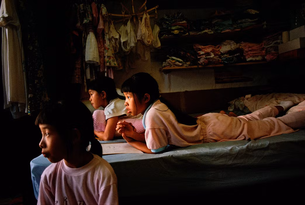 Những đứa trẻ trong căn hộ của một gia đình công nhân may mặc ở khu Chinatown. Ảnh: Chien-Chi Chang/ Magnum Photos.