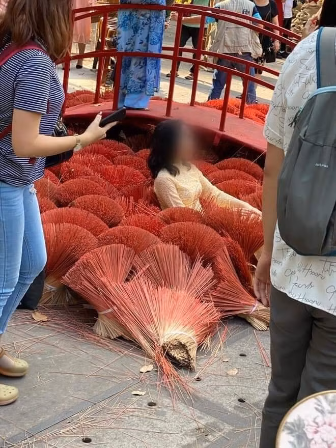 Theo những hình ảnh được đăng tải, một khoảng sân được xếp nhiều bó hương đỏ đẹp mắt để trang trí, tuy nhiên, điều đáng nói là có 2 người phụ nữ mặc áo dài, thoải mái nằm đè thẳng xuống những bó hương rồi tươi cười tạo dáng để chụp ảnh khiến nhiều người nóng mắt.