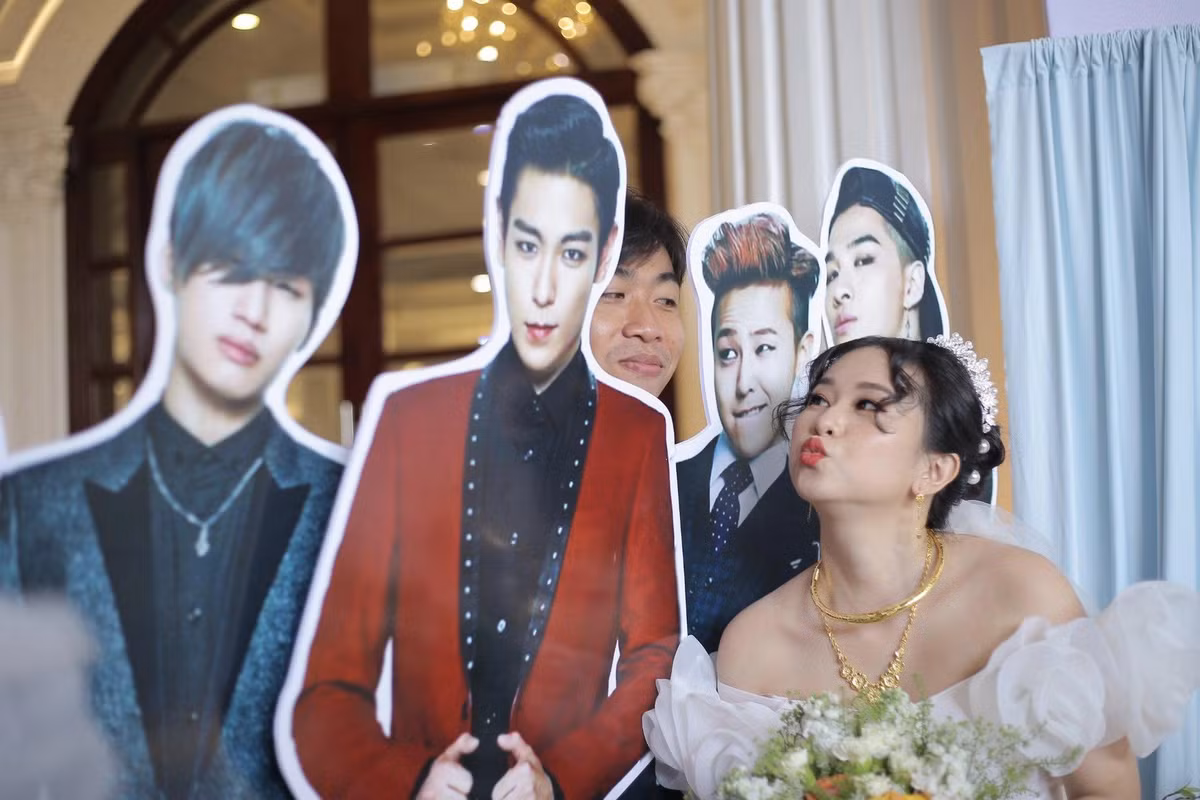 Điều đáng chú ý trong đám cưới độc đáo này chính là xuất hiện Standee hình các thành viên của nhóm nhạc đình đám Big Bang, thiệp, hoa cưới và trang trí hôn trường gắn với hình ảnh của nhóm nhạc Hàn Quốc này.