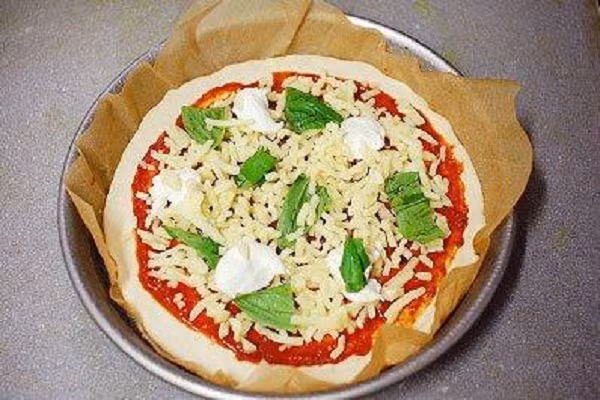 Tiếp theo rắc pho mát, rau chân vịt, có thể một ít topping kem, dầu ô liu, gia vị làm pizza và bột phô mai rồi cho vào lò nướng 180 độ trong vòng 15 phút. Trước khi nướng nhớ làm nóng lò trước nhé. (Ảnh: banh.com.vn)