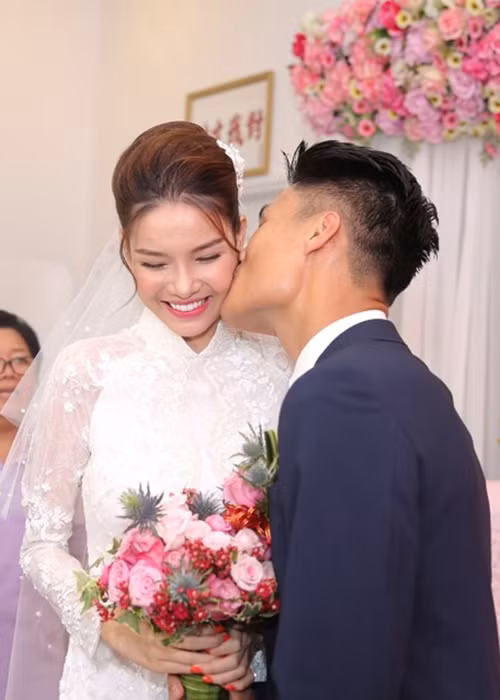 Nữ người mẫu 9x xinh đẹp trong bộ áo dài ren trắng. Cô tỏ ra khá bối rối khi nhận nụ hôn từ Mạc Hồng Quân. (Ảnh: Tiền phong)
