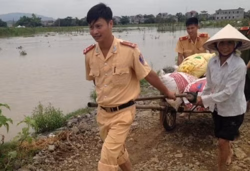 Hồi tháng 5/2016, các chiến sĩ công an, cảnh sát giao thông, dân phòng của huyện Nho Quan, Ninh Bình xắn quần, bỏ dép gặt lúa giúp dân chạy lũ. Nguồn ảnh: Phạm Tấn Đạt.