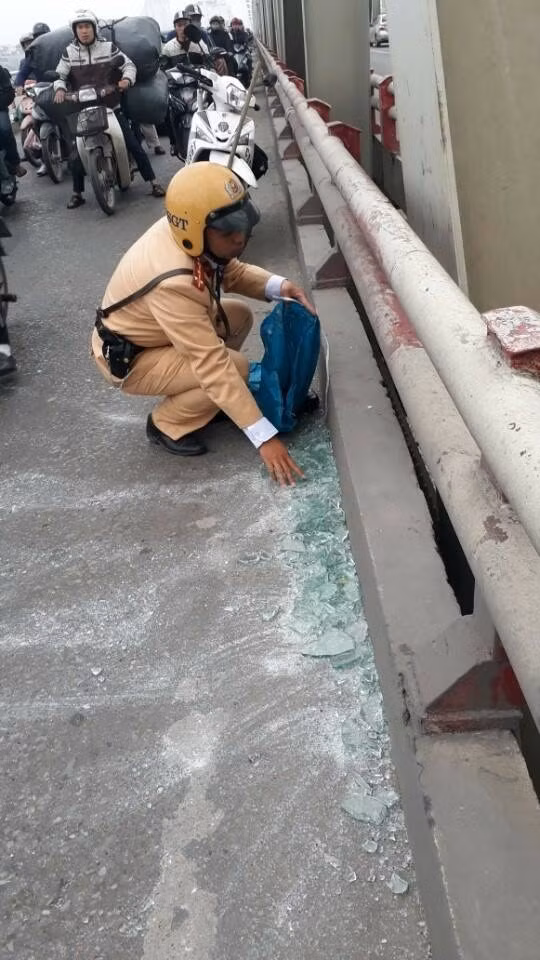 Do chỉ có một chiếc chổi nên CSGT phải dùng tay bốc những mảnh kính vỡ cho vào túi.