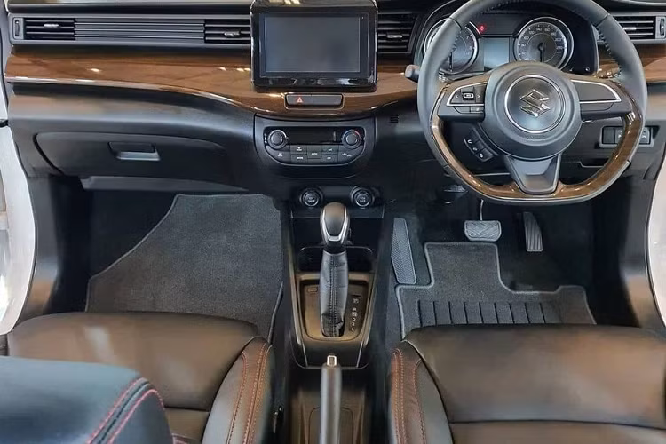 Ở bên sườn, Suzuki Ertiga Sport FF 2022 được trang bị các cột sơn màu đen, tạo hiệu ứng "nóc lơ lửng". Bên cánh đó là ốp gương ngoại thất màu đen với đường kẻ đỏ và đề-can màu đen mới trên cửa theo phong cách xe đua. Đáng tiếc là xe vẫn dùng vành có đường kính chỉ 15 inch. Vòng ra phía sau, chúng ta sẽ bắt gặp cánh gió mui cỡ lớn và dải đèn màu đỏ mới, nối giữa 2 cụm đèn hậu.