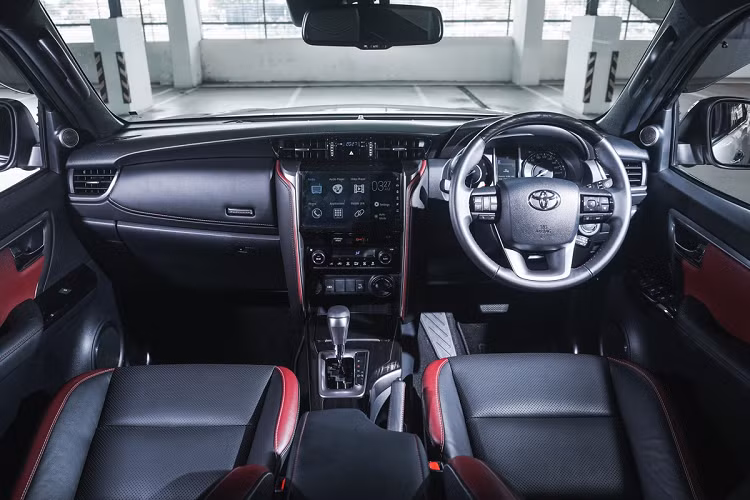 Nội thất của Toyota Fortuner được phối 2 màu đen và đỏ. Khu vực điều khiển trung tâm gồm màn hình thông tin giải trí cảm ứng 8 inch tích hợp kết nối Apple CarPlay/Android Auto, dàn âm thanh 11 loa JBL và sạc điện thoại không dây.