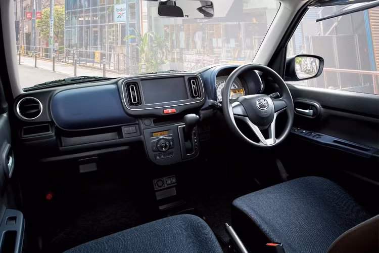 Xe vẫn có vô lăng mới nhưng không tích hợp phím chỉnh âm lượng và kết nối Bluetooth như Suzuki Alto 2022. Bảng đồng hồ sau vô lăng có thêm màn hình LCD nhỏ nằm ngang mới. Đáng tiếc là Mazda Carol 2022 không có màn hình thông tin giải trí dạng cảm ứng 7 inch tùy chọn như Suzuki Alto. Do đó, ở giữa 2 cửa gió điều hòa trung tâm nằm dọc chỉ là một tấm nhựa màu đen.