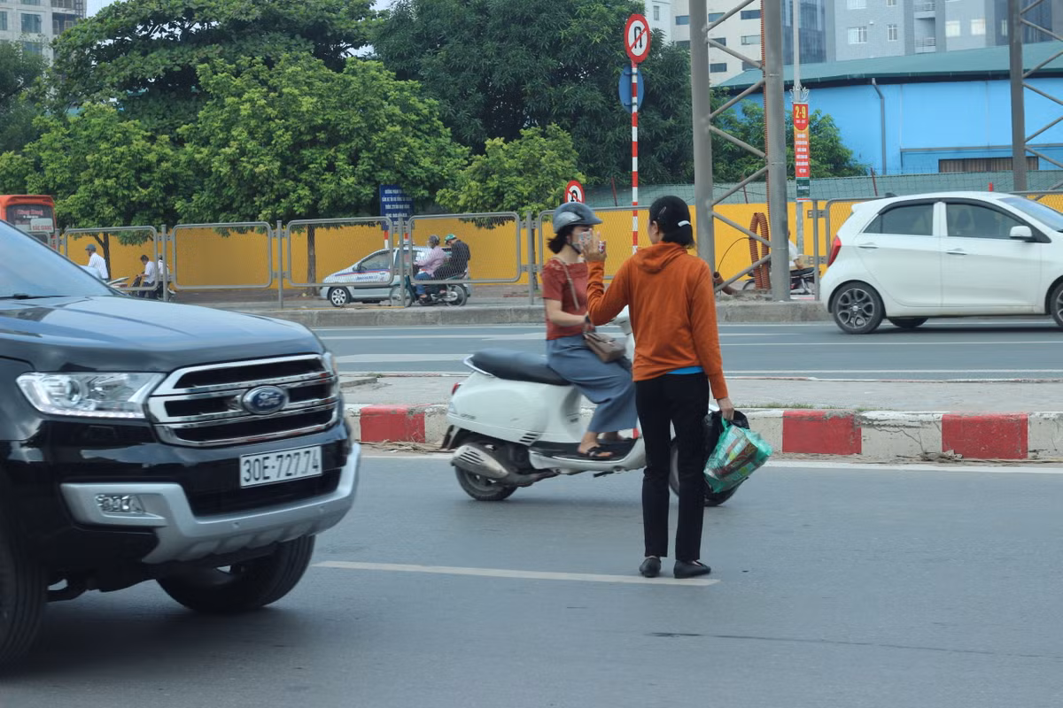 Người dân bất chấp nguy hiểm băng qua đường đi về phía đường Vành đai 3 trên cao để bắt xe khách.