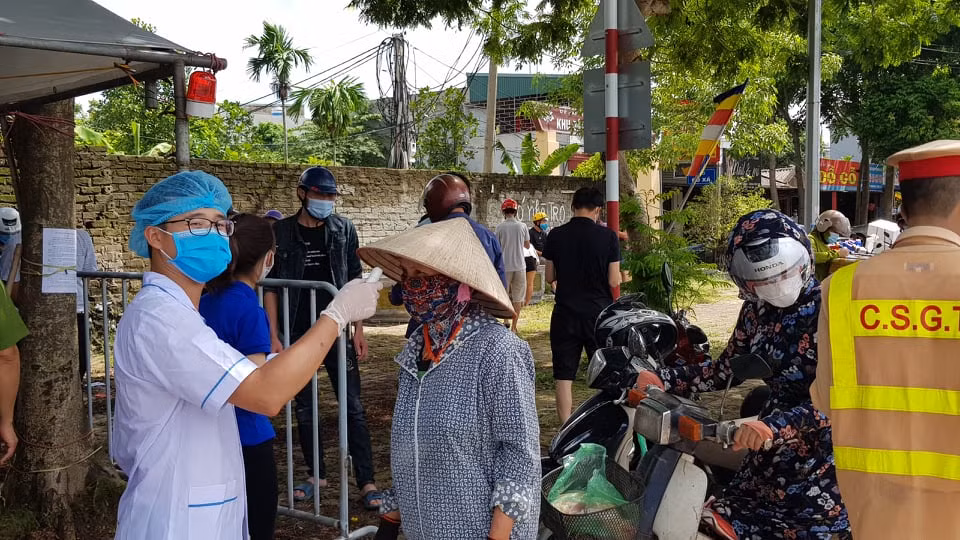Nhân viên y tế kiểm tra thân nhiệt người dân qua chốt.