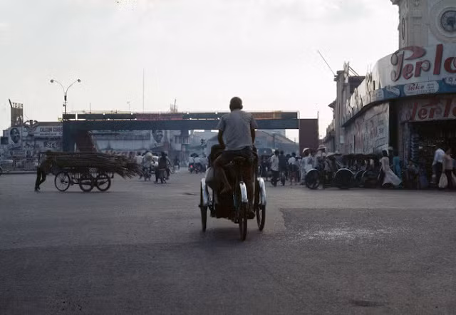 Người lái xích lô chở đầy hàng hóa trên đường phố Sài Gòn.
