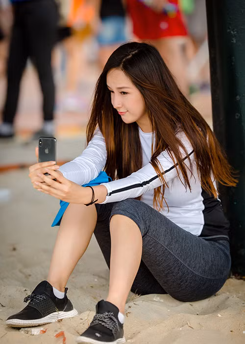 Sau khi chạy bộ, Mai Phương Thúy ngồi bệt trên cát để nghỉ ngơi.