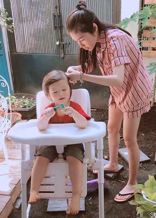 Hình ảnh bé Túc Mạch ngồi ngoan ngoãn để mẹ cắt tóc.