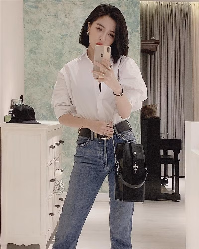 hời tiết bắt đầu nóng nực là thời điểm thích hợp cho những chiếc sơ mi lên ngôi. Bích Phương phối sơ mi trắng với quần jeans cạp cao kèm chiếc túi basic tông đen.