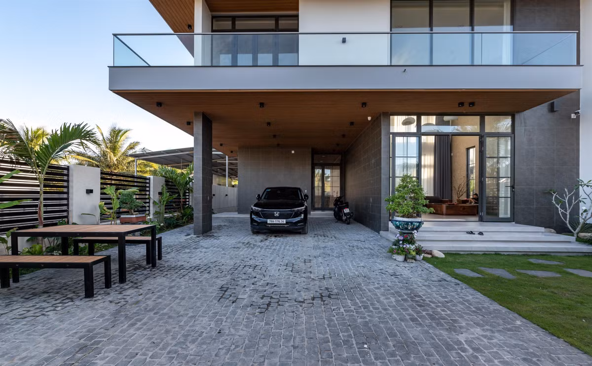 Kiến trúc sư SIMBA Architects dành riêng một khoảng không gian sân “nửa ngoài nửa trong” để đáp ứng được hai công năng cùng lúc là đậu xe và là khu vực tổ chức các bàn tiệc đãi khách mỗi dịp lễ, tết.