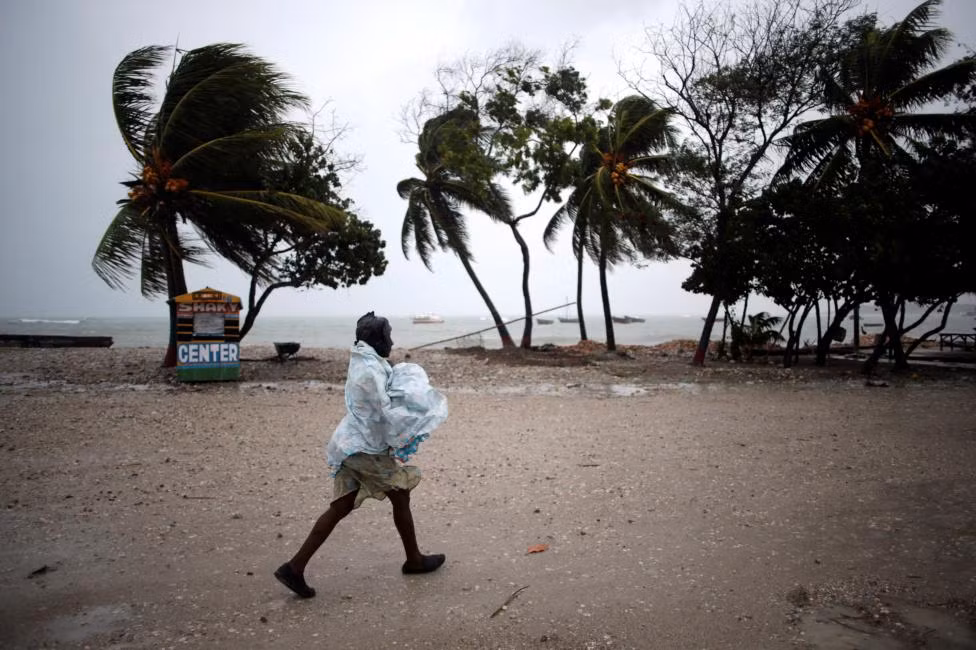 Người phụ nữ co ro giữa trời mưa ở Les Cayes, Haiti.