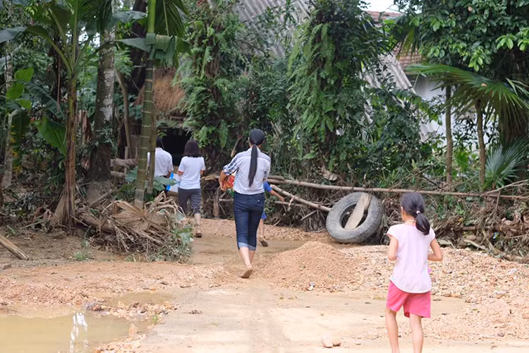 Người đẹp không ngại di chuyển trên những con đường trơn trượt dính đầy bùn đất hay lội nước để đến với bà con.