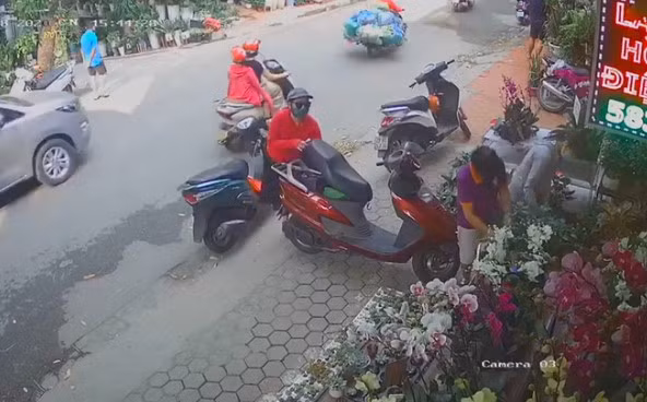 Theo đó, đoạn video camera ghi lại cảnh một nữ khách hàng dựng xe trên vỉa hè rồi vào cửa hàng hoa. Trong khi vị khách đang mải mê chọn thì một người phụ nữ khác, mặc áo đỏ đi xe máy từ từ tiến tới, rồi nhanh tay cậy cốp xe của vị khách nữ kia nhưng bất thành.