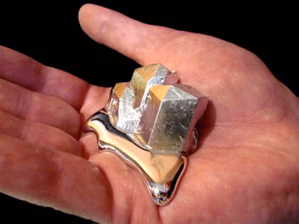 Gallium Metal - Kim loại tan chảy trong tay người là chất không tồn tại trong tự nhiên, nhưng dễ dàng tìm thấy sau các phản ứng nung chảy nhôm, kẽm... và được chiết xuất từ dầu thô hydroxide nhôm.