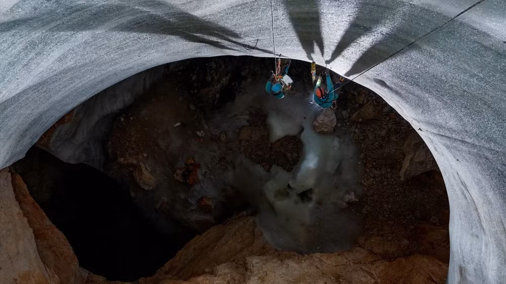 Sau bức tường băng cao 22 mét, nhà cổ sinh vật học Tanguy Racine (ở bên phải) và một đồng nghiệp dừng lại để lấy một mẫu của nó. Racine đã phát hiện ra rằng lớp băng gần đáy của hang động sâu 100 mét này có thể đã 5.300 năm tuổi. Băng đã tích tụ ở đây trong gần 2.000 năm qua. Ảnh: National Geographic